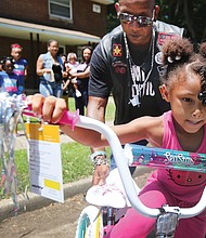 Ready to roll //
Shy’Tia Henry, 5, takes off with the help of Corey “Cool” Brown of Petersburg as she tries out her new bike last Saturday at the Fairfield Court Community Day. She won one of several bicycles that were raffled off during the neighborhood event. Mr. Brown is a member of one of the motorcycle clubs that sponsored the bike giveaway. Location: 2300 block of North 25th Street.