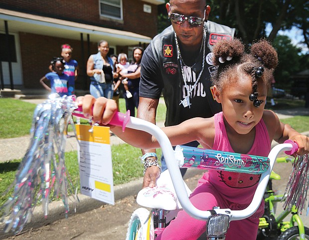 Ready to roll //
Shy’Tia Henry, 5, takes off with the help of Corey “Cool” Brown of Petersburg as she tries out her new bike last Saturday at the Fairfield Court Community Day. She won one of several bicycles that were raffled off during the neighborhood event. Mr. Brown is a member of one of the motorcycle clubs that sponsored the bike giveaway. Location: 2300 block of North 25th Street.