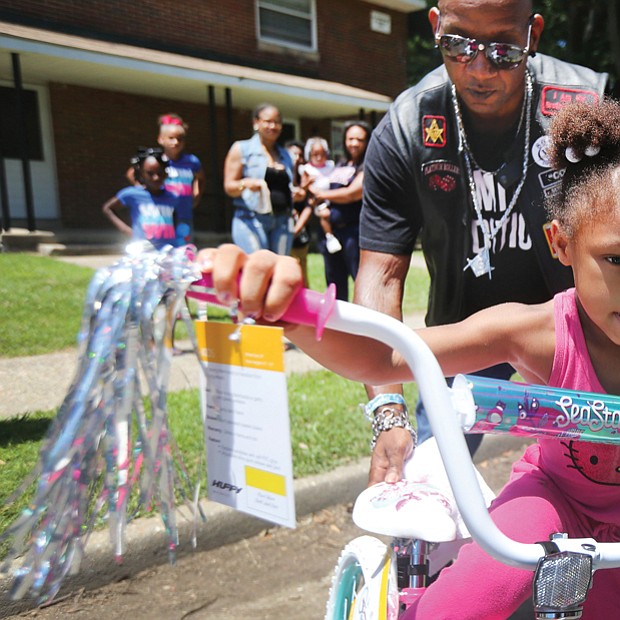 Ready to roll //
Shy’Tia Henry, 5, takes off with the help of Corey “Cool” Brown of Petersburg as she tries out her new bike last Saturday at the Fairfield Court Community Day. She won one of several bicycles that were raffled off during the neighborhood event. Mr. Brown is a member of one of the motorcycle clubs that sponsored the bike giveaway. Location: 2300 block of North 25th Street.