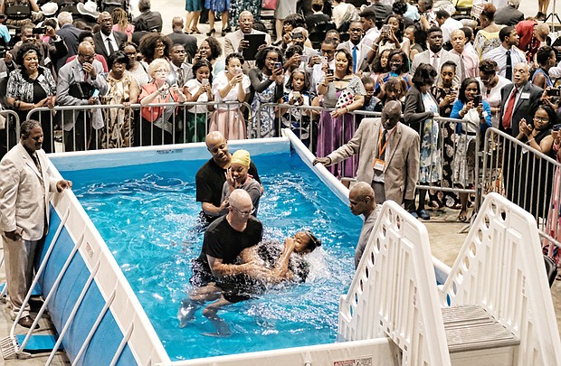 Alajah Johnson, front, holds her nose while she is baptized by David Lowe, and Kijah Powers gets ready for her baptism with Spencer Spinner. The two were among 29 people baptized last Saturday during the Jehovah’s Witnesses convention at the Richmond Coliseum in Downtown. It was the first of a series of three-day weekend conventions by the denomination. The series concludes Aug. 4 through 6.