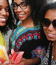 Sisters Chynna and Krystle Harrell enjoy a tropical fruit cup with their cousin, Shakeema Edwards, at the festival.