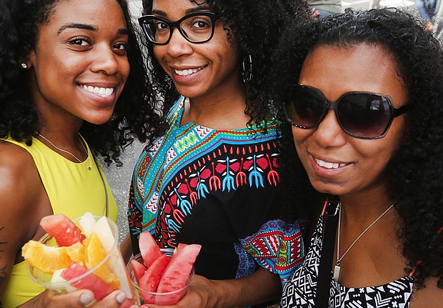 Sisters Chynna and Krystle Harrell enjoy a tropical fruit cup with their cousin, Shakeema Edwards, at the festival.