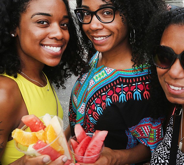 Sisters Chynna and Krystle Harrell enjoy a tropical fruit cup with their cousin, Shakeema Edwards, at the festival.