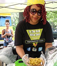 Beverly McFarland of In the Raw with Soul hands vegan macaroni and cheese to a patron.