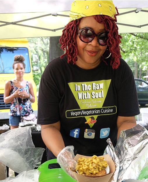 Beverly McFarland of In the Raw with Soul hands vegan macaroni and cheese to a patron.