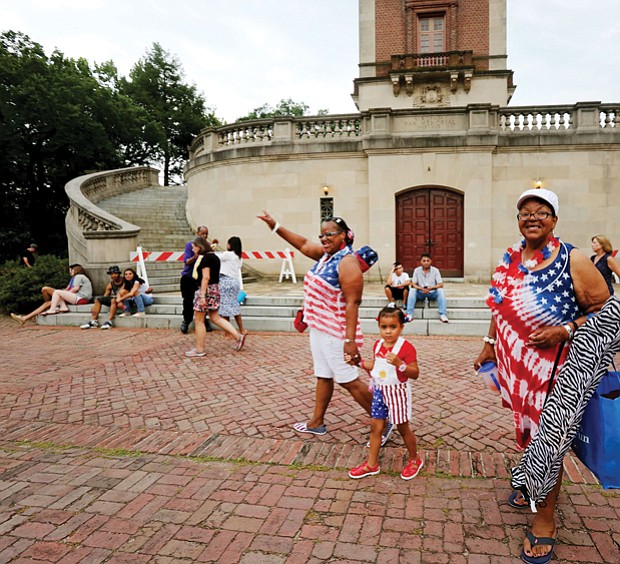 Wearing red, white and blue, Paulette Frye, left, leads her granddaughter, Maria Miles, 4, and her sister, Claudette Miles, to Dogwood Dell by the Carillon in Byrd Park, where hundreds of people on Tuesday spread blankets, put up lawn chairs and brought picnic baskets filled with goodies to enjoy music and entertainment before the annual fireworks display.
