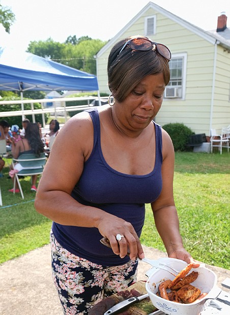 Veda Gilmore takes food off the grill on Tuesday during the annual July Fourth neighborhood cookout in her backyard at 25th and W streets in Church Hill.