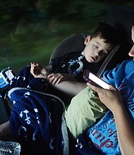 Gabe Michot, 4, holds his mother's arm as he sleeps on the bus trip from Louisiana to Washington to speak against health care reform.