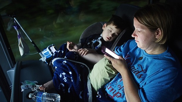 Gabe Michot, 4, holds his mother's arm as he sleeps on the bus trip from Louisiana to Washington to speak against health care reform.