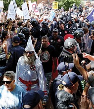 Police protect members of the Loyal White Knights of the Ku Klux Klan from counterprotesters as they arrive at Justice Park in Charlottesville for a rally last Saturday objecting to City Council’s vote to remove Confederate monuments from two city parks.  
