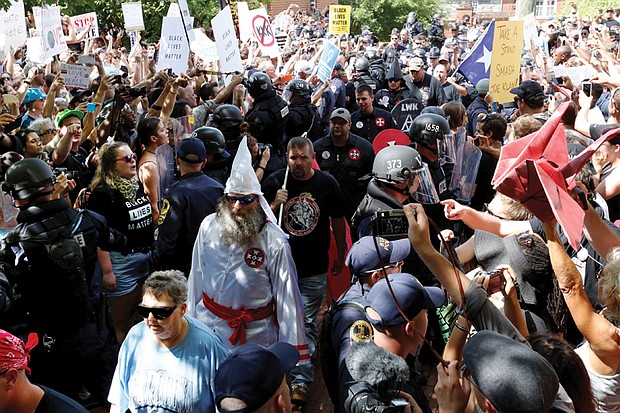 Police protect members of the Loyal White Knights of the Ku Klux Klan from counterprotesters as they arrive at Justice Park in Charlottesville for a rally last Saturday objecting to City Council’s vote to remove Confederate monuments from two city parks.  

