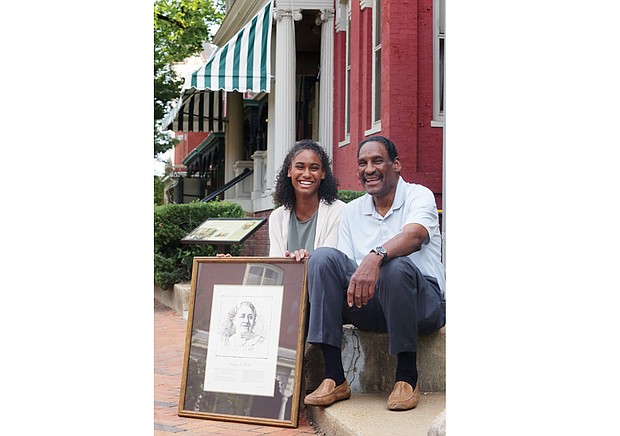 Dr. Johnny Mickens III, great-grandson of Maggie L. Walker, and his daughter, Liza, 19, hold a portrait of the Richmond pioneer outside of the Maggie L. Walker National Historic Site at 110½ E. Leigh St. in Jackson Ward where Mrs. Walker lived.