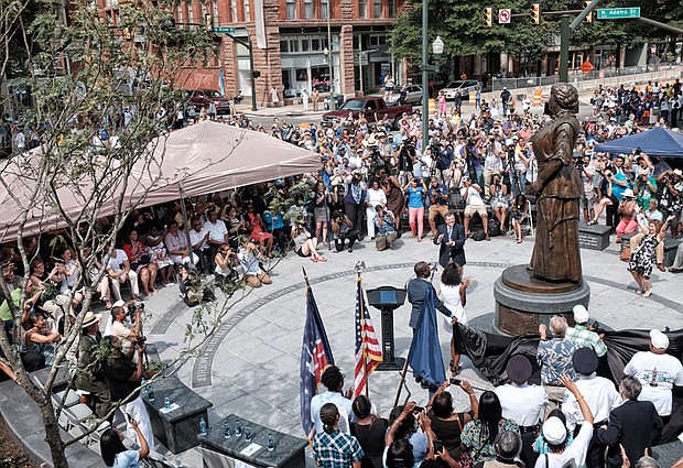 Cheers arise from the crowd of hundreds after the statue of Maggie L. Walker is unveiled at a ceremony last Saturday at the plaza at Broad and Adams streets. 