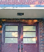 A weathered side entrance and light fixture at the school show some of the work that needs to be done.