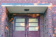 A weathered side entrance and light fixture at the school show some of the work that needs to be done.