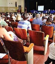 Richmond Public Schools Interim Superintendent Tommy Kranz addresses a packed auditorium during Monday’s public hearing on conditions at George Mason Elementary School in the East End. Below, Hope Talley, a fourth-grade teacher at George Mason Elementary, wears a mask to prevent her allergies from flaring up. She said they are aggravated by mold in the building.