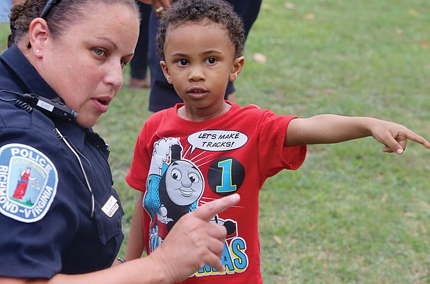 In the right direction //
Three-year-old Tristian Levere of Henrico County directs the attention of Richmond Police Office Monica Fecht on Tuesday to a spot at Pollard Park during National Night Out festivities. The youngster built his own connection with the officer at the event to strengthen neighborhoods, reduce crime and build connections. Please see more photos, A2.
