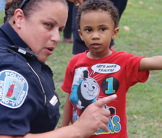 In the right direction //
Three-year-old Tristian Levere of Henrico County directs the attention of Richmond Police Office Monica Fecht on Tuesday to a spot at Pollard Park during National Night Out festivities. The youngster built his own connection with the officer at the event to strengthen neighborhoods, reduce crime and build connections. Please see more photos, A2.
