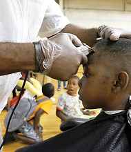 On the cutting edge //
Jakhai Wilson, 9, sits perfectly still as Damond Gurley of the Virginia Barber School puts the final touches on his new haircut. Jakhai got the free cut while participating in the WE CARE/Northside Coalition for Children Back-to-School Rally and Festival last Saturday at the Hotchkiss Field Community Center in Highland Park. The festive event included the donation of hundreds of bookbags stuffed with school supplies to students like Jakhai as they get ready to head back to classes next month. 