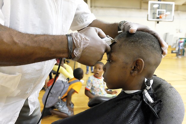 On the cutting edge //
Jakhai Wilson, 9, sits perfectly still as Damond Gurley of the Virginia Barber School puts the final touches on his new haircut. Jakhai got the free cut while participating in the WE CARE/Northside Coalition for Children Back-to-School Rally and Festival last Saturday at the Hotchkiss Field Community Center in Highland Park. The festive event included the donation of hundreds of bookbags stuffed with school supplies to students like Jakhai as they get ready to head back to classes next month. 