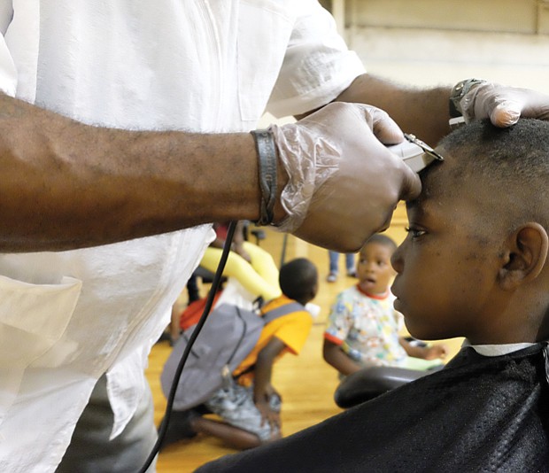 On the cutting edge //
Jakhai Wilson, 9, sits perfectly still as Damond Gurley of the Virginia Barber School puts the final touches on his new haircut. Jakhai got the free cut while participating in the WE CARE/Northside Coalition for Children Back-to-School Rally and Festival last Saturday at the Hotchkiss Field Community Center in Highland Park. The festive event included the donation of hundreds of bookbags stuffed with school supplies to students like Jakhai as they get ready to head back to classes next month. 