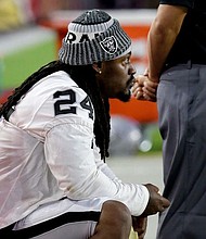 Oakland Raiders running back Marshawn Lynch (24) sits during the national anthem prior to the team’s NFL preseason football game against the Arizona Cardinals, Saturday, Aug. 12, 2017, in Glendale, Ariz. (AP Photo/Rick Scuteri)