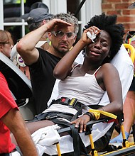 Rescue workers help a woman who was injured when a white nationalist rammed his car into a crowd of counterprotesters. Several of the 19 people injured are in critical condition.