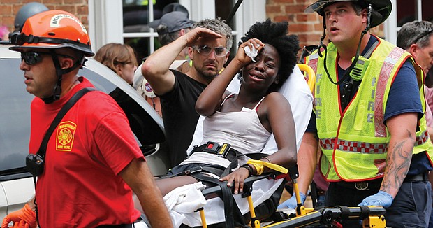 Rescue workers help a woman who was injured when a white nationalist rammed his car into a crowd of counterprotesters. Several of the 19 people injured are in critical condition.