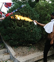 Corey Long uses a lighted spray can to repel a white nationalist Saturday at the entrance to Emancipation Park. Mr. Long later told reporters that one of the white supremacists had put a gun to his head and then fired a shot into the ground by his foot.