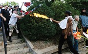 Corey Long uses a lighted spray can to repel a white nationalist Saturday at the entrance to Emancipation Park. Mr. Long later told reporters that one of the white supremacists had put a gun to his head and then fired a shot into the ground by his foot.