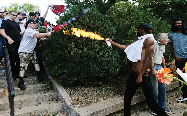Corey Long uses a lighted spray can to repel a white nationalist Saturday at the entrance to Emancipation Park. Mr. Long later told reporters that one of the white supremacists had put a gun to his head and then fired a shot into the ground by his foot.