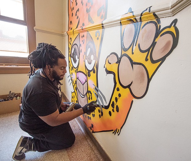 Silly, a local artist, paints the school’s mascot, a Jaguar, on the landing of a stairwell. 