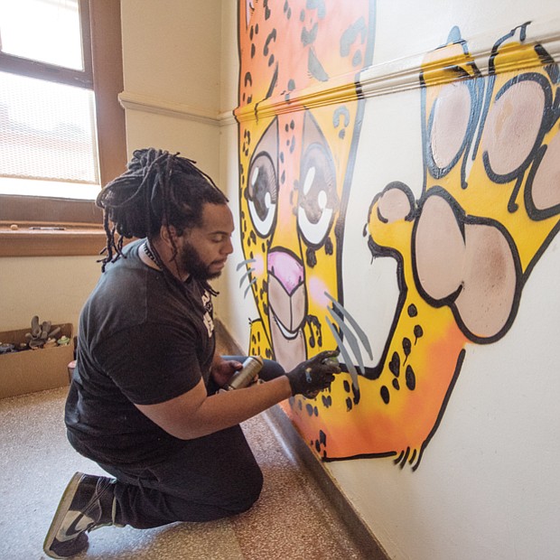 Silly, a local artist, paints the school’s mascot, a Jaguar, on the landing of a stairwell. 