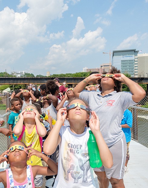 Solar phenomenon //
Richmonders by the hundreds took to parks, front yards and rooftops Monday to witness the phenomenal solar eclipse. The rare total eclipse was visible across the entire United States, from Oregon to South Carolina. In the Richmond area, the moon covered about 85 percent of the sun during the 2-minute climax about 2:44 p.m. Left, youngsters with the Richmond Department of Parks, Recreation and Community Facilities, led by Shanna Battle,