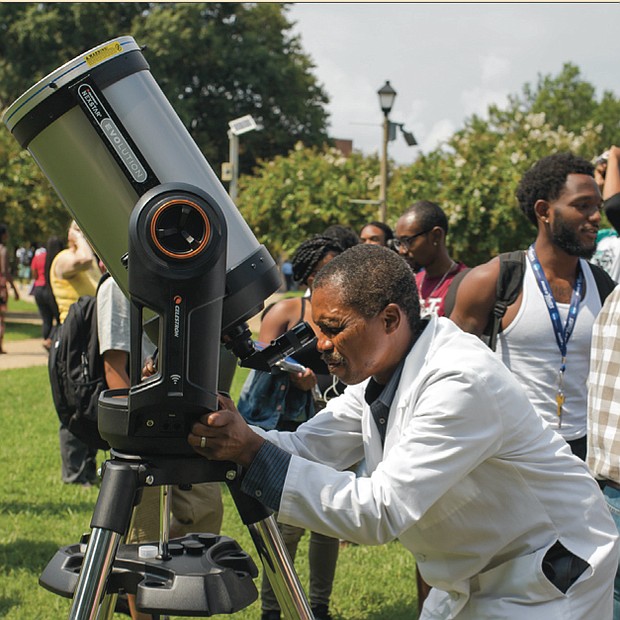 Solar phenomenon // use approved eclipse glasses to view the event from the T. Tyler Potterfield Memorial Bridge in Downtown. Dr. Francis E. Mensah, assistant professor of physics at Virginia Union University, sets up on the university’s lawn as spectators gather to view the eclipse.
