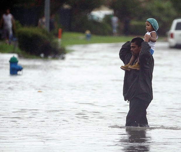 Charlie Riedel/ Associated Press
A man carries a child across a flooded street in Houston on Sunday as they search for higher ground.