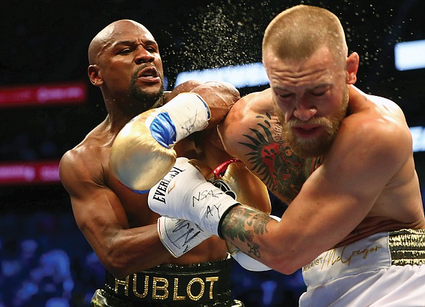 Boxer Floyd Mayweather Jr., left, lands a punch on Conor McGregor, a mixed martial arts champion, during last Saturday’s boxing match at the T-Mobile Arena in Las Vegas.
