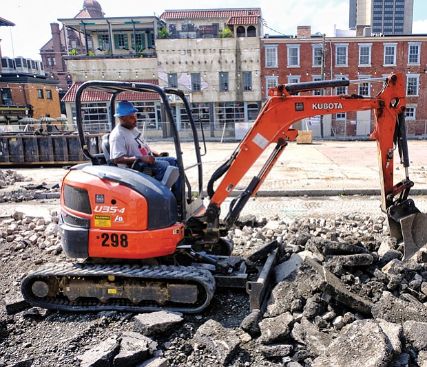 
A worker digs up cobblestones that covered a now closed stretch of 17th Street in Shockoe Bottom. The work is part of the estimated $4.3 million facelift for the Farmers’ Market area, which dates to the 1780s and is among the oldest such marketplaces in the country. The old pavilions, concrete and stones are being removed between Main and Franklin streets to create a European-style plaza with market stalls on the side and an open space for local and regional events. The outdoor setting that is to be finished next year is designed to complement the revamped Main Street Station with its grand indoor event space. Despite the work, businesses located along the street are still open and accessible by the sidewalk.