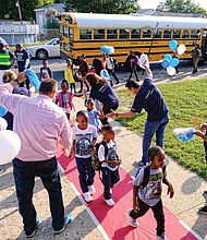 Students are greeted Tuesday at George Mason Elementary School by a cheering squad of volunteers from Capital One. Principal Rose Ferguson and interim Superintendent Thomas E. “Tommy” Kranz are the initial greeters by the school bus door.