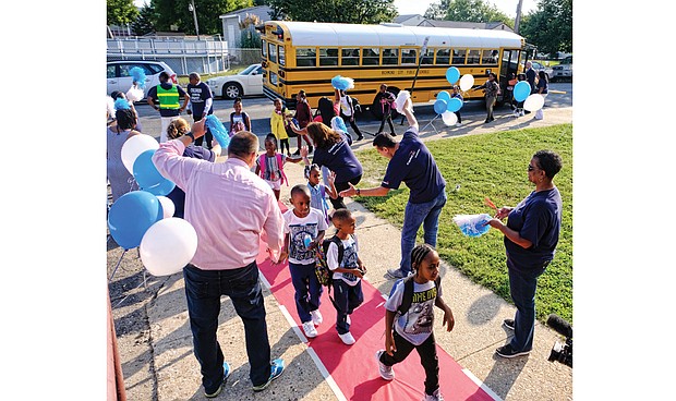 Students are greeted Tuesday at George Mason Elementary School by a cheering squad of volunteers from Capital One. Principal Rose Ferguson and interim Superintendent Thomas E. “Tommy” Kranz are the initial greeters by the school bus door.