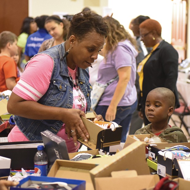 Sharon Toulson of Sharon Baptist Church helps 4-year-old Joshua Ellis choose the perfect pair of shoes.