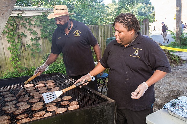 Alonzo Coley keep a watchful eye on hamburgers cooking on the grill at the event hosted by members of the 26th Masonic District and the Richmond Police Department in Church Hill. 