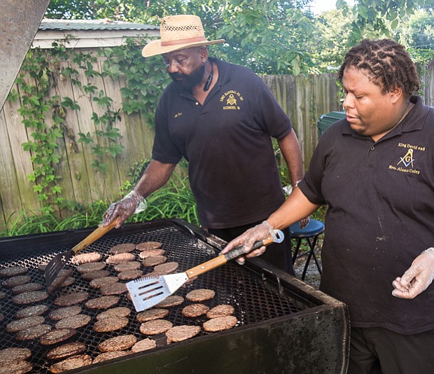 Alonzo Coley keep a watchful eye on hamburgers cooking on the grill at the event hosted by members of the 26th Masonic District and the Richmond Police Department in Church Hill. 