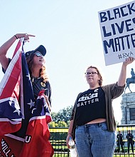 Tara Brandau, a Florida resident and organizer with the pro-Confederate CSA II group, expresses her support for the Lee statue while counterprotester Taylor Medley holds a sign with her opposing sentiment. 