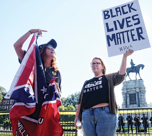 Tara Brandau, a Florida resident and organizer with the pro-Confederate CSA II group, expresses her support for the Lee statue while counterprotester Taylor Medley holds a sign with her opposing sentiment. 