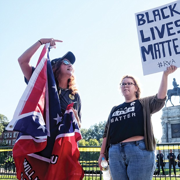 Tara Brandau, a Florida resident and organizer with the pro-Confederate CSA II group, expresses her support for the Lee statue while counterprotester Taylor Medley holds a sign with her opposing sentiment. 