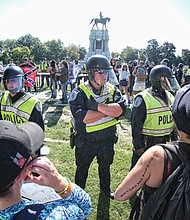 Richmond police officers in riot gear separate counterprotesters from neo-Confederates on the west side of the Robert E. Lee monument. The small number of Confederate statue supporters was vastly outnumbered by hundreds of counterprotesters.