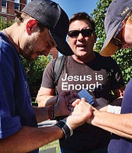 Jason Collier joins the hands of a protester and counterprotester to pray near the Lee statue in the midst of the rally.