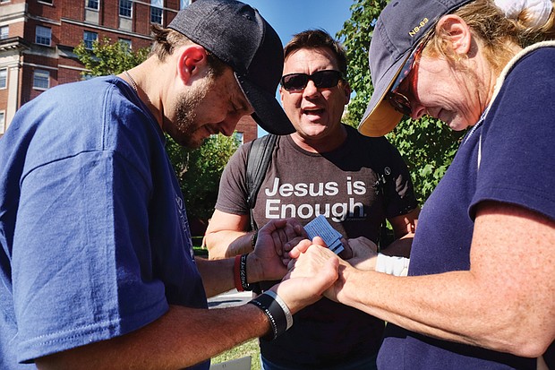 Jason Collier joins the hands of a protester and counterprotester to pray near the Lee statue in the midst of the rally.