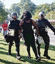 Police detain an unidentified counterprotester for singing rap music using a microphone and speaker on the grassy median on Monument Avenue between Meadow Street and Allen Avenue. With a semiautomatic rifle over his shoulder, CSA II organizer Thomas Crompton of Tennessee argues his point of view